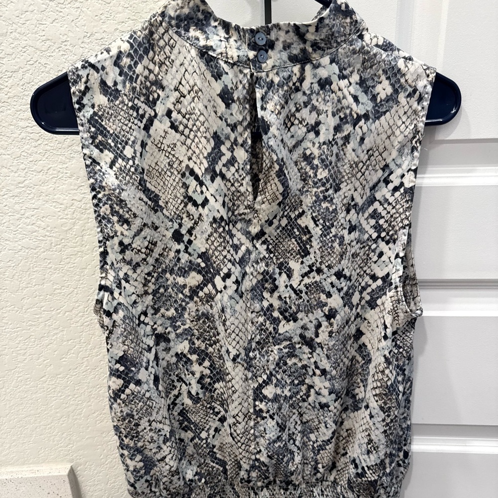 High neck Sleeveless blouse, small opening in front and button-down back.